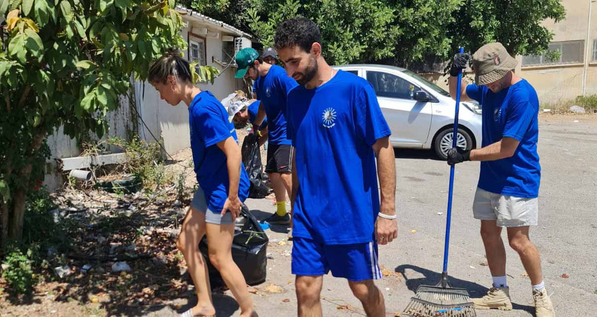 מתנדבים חבריו של רס"ן (מיל) נצר שמחי ז"ל מנקים את גינת נווה הדר בחבצלת השרון, הם לבושים בחולצה כחולה של הקבוצה