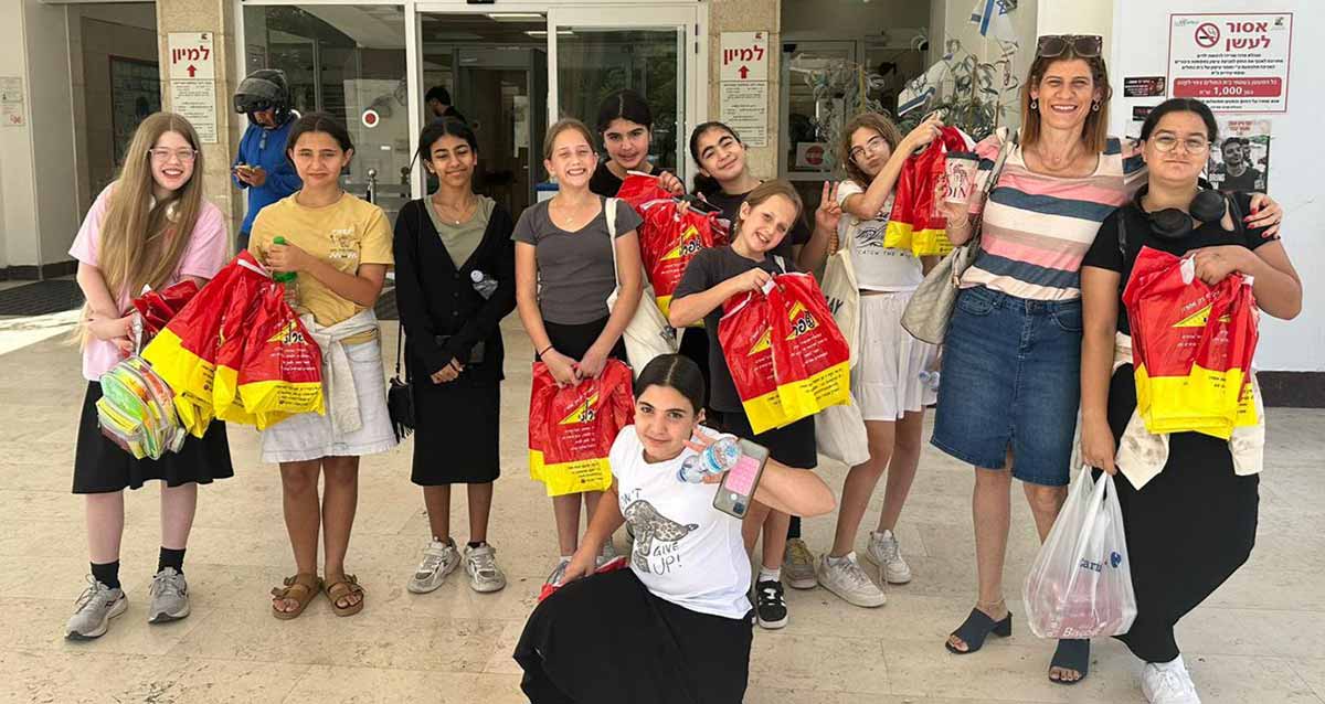 תלמידות כיתה ו' בבית ספר אריאל בגני תקווה בתצלום קבוצתי עומדות עם שקיות של מתנות, שקיות בצבעים אדום וצהוב