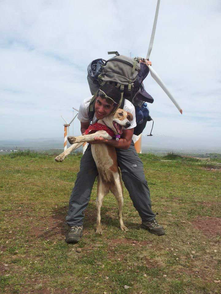אסף דגן עם תרמיל גדול על גבו. מחבק כלב