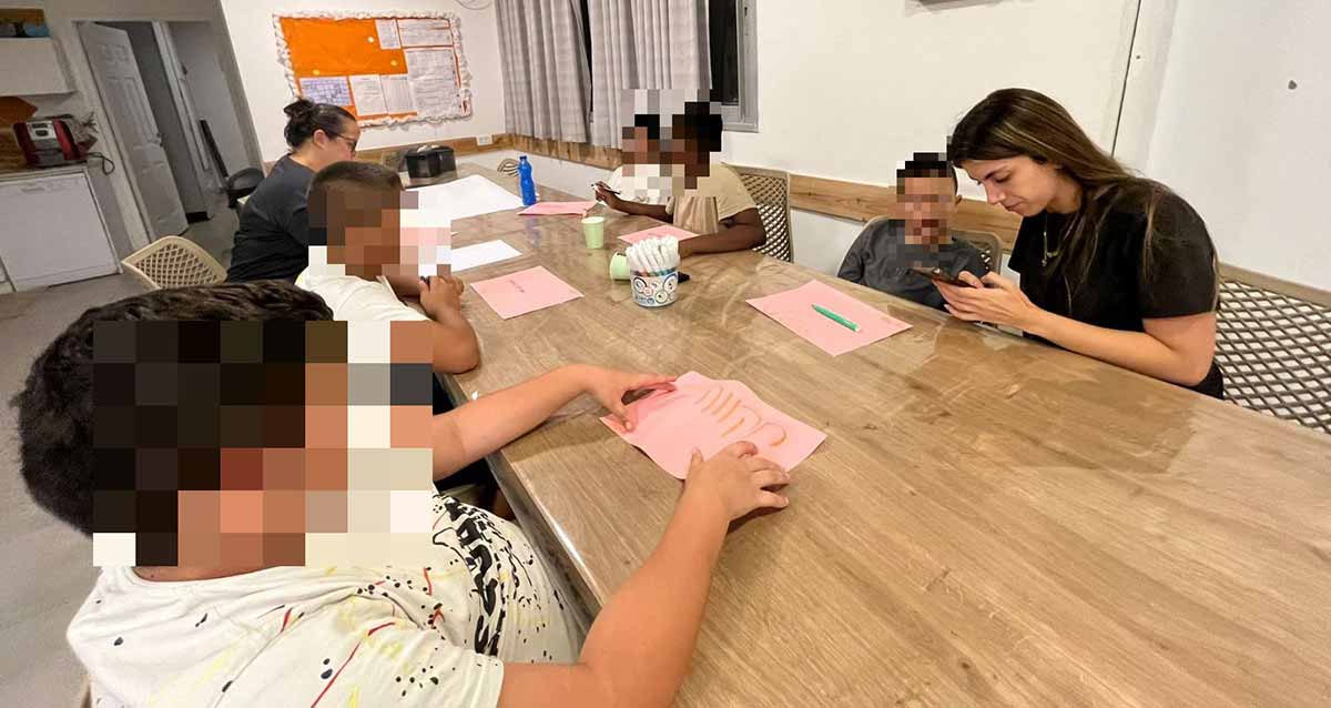 פרויקט "אפייטוקאייר" בכפר הילדים והנוער טוקאייר. הנוער יושב מסביב לשולחן ארוך ובצד ימין מדריכה.