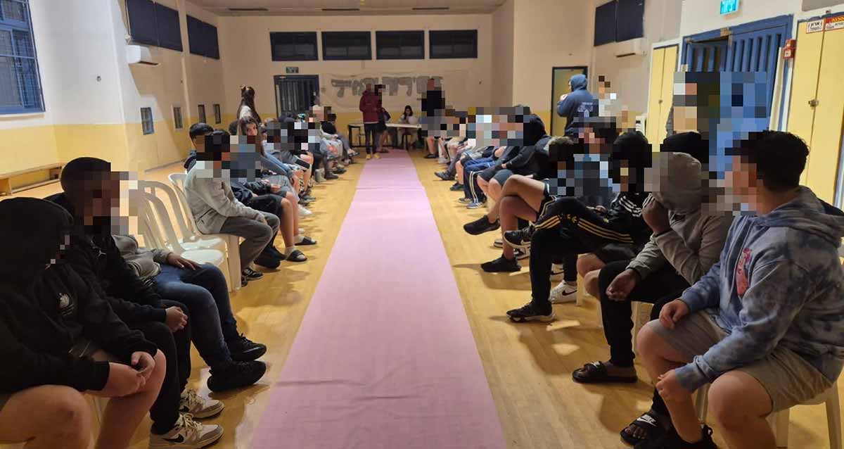 פרויקט "אפייטוקאייר" בכפר הילדים והנוער טוקאייר. הנוער יושב בשתי שורות, שורה מול שורה, לאורך אולם, וביניהם שטיח ורוד.