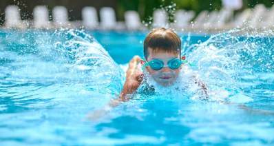 ילד מקבוצת שחייה פראלימפית בבריכת שחייה עם משקפי שחיה כחולים.