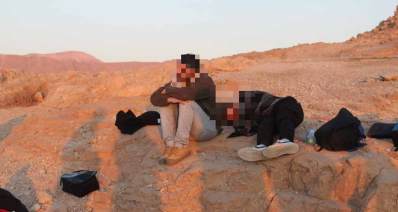 בוגרי פנימיית רבדים בטיול סיום. שני מטיילים נחים על הקרקע. אחד יושב והשני שוכב.