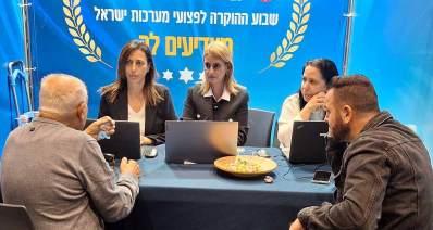 שבוע הוקרה לפצועי מערכות ישראל. סביב שולחן עם מחשבים ניידים יושבים שלוש נשים ושני גברים. מאחוריהם פלקט עם הכיתוב: שבוע ההוקרה לפצועי מערכות ישראל, ושני עלי זית בימין ובשמאל.