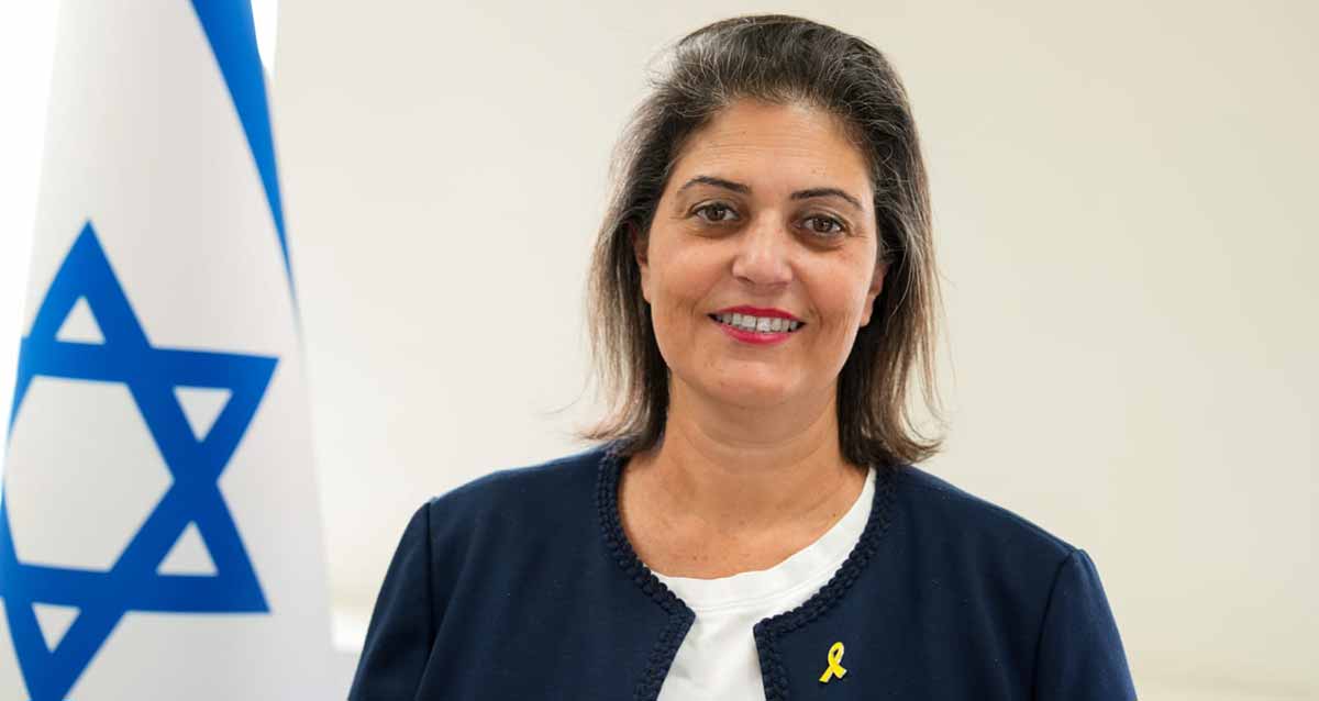 אתי קיסוס, סמנכ"ל וראש מינהל שירותים חברתיים, משרד הרווחה והביטחון החברתי. צילום פלג גוף עליון, ודגל המדינה בצד שמאל. צילום: אילן בנדנה