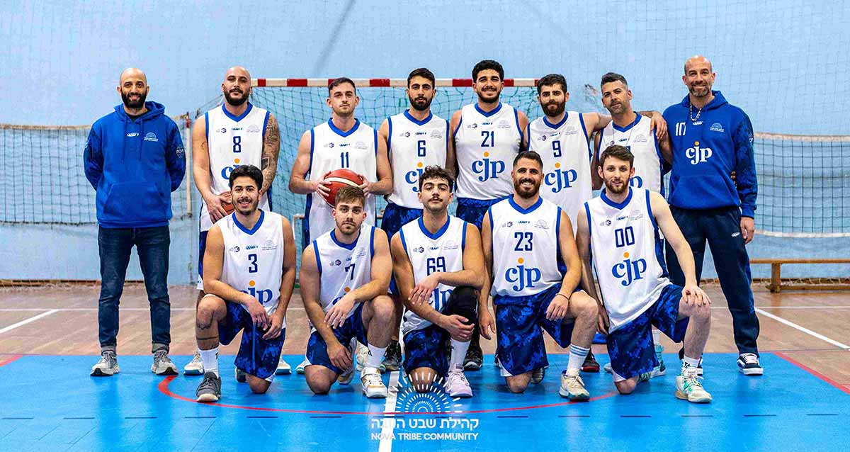 קבוצת הכדורסל של קהילת שבט הנובה. 11 שחקנים ושני מאמנים בצילום קבוצתי, חמישה כורעים ברך ושישה עומדים אחריהם. המאמנים בשני הצדדים. שחקן אחד עם כדורסל ביד. מאחוריהם שער עם רשת.