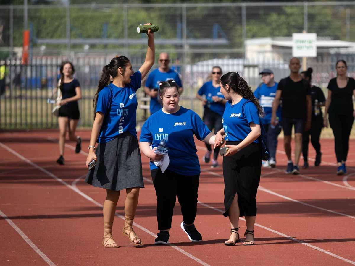 מרוץ איתן RUN. שלוש רצות בחזית על משטח חום, ואחת מניפה פחית ירוקה. ואחריהן רצים ורצות.