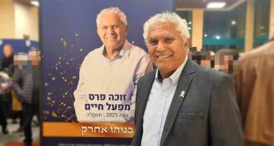 בניהו אחרק מנכ"ל אקים חדרה מקבל פרס מפעל חיים ולידו עוד אדם, שלט בחזית התמונה עם הכיתוב: זוכה פרס מפעל חיים שנת 2025 תשפ"ה, בניהו אחרק.