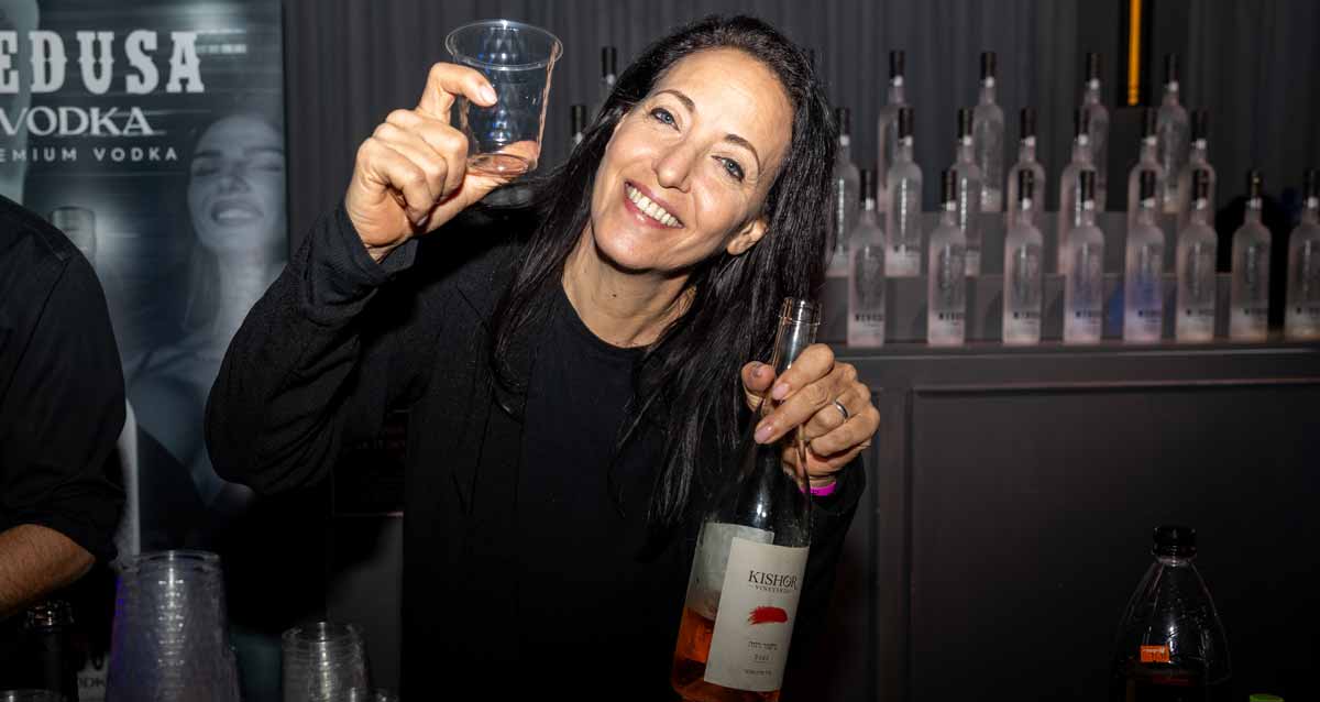 ליהיא לפיד בנשף פורים של עמותת שניר עם בקבוק וכוס בידיים.