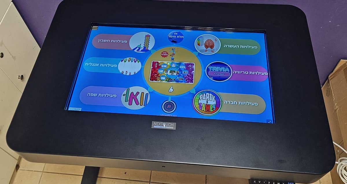 פתרונות טכנולוגיים בחינוך המיוחד ברעננה. שולחן אינטראקטיבי ומסך מגע. במסך מוצגים 6 נושאים: פעילויות העשרה, פעולות טריוויה, פעילויות חברתיות, פעילויות חשבון, פעילויות אנגלית, פעילויות שפה.