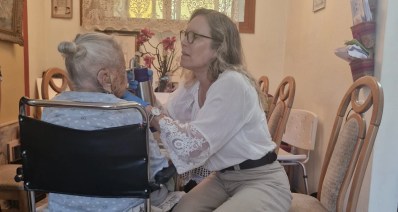 רופאה מתנדבת מטפלת בניצולת שואה בכסא גלגלים.