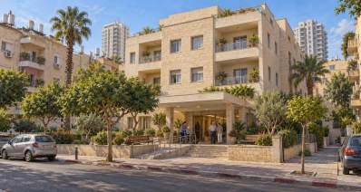 איור חיצוני של בית אבות סיעודי בסביבה עירונית ישראלית, עם כניסה נגישה וצמחייה